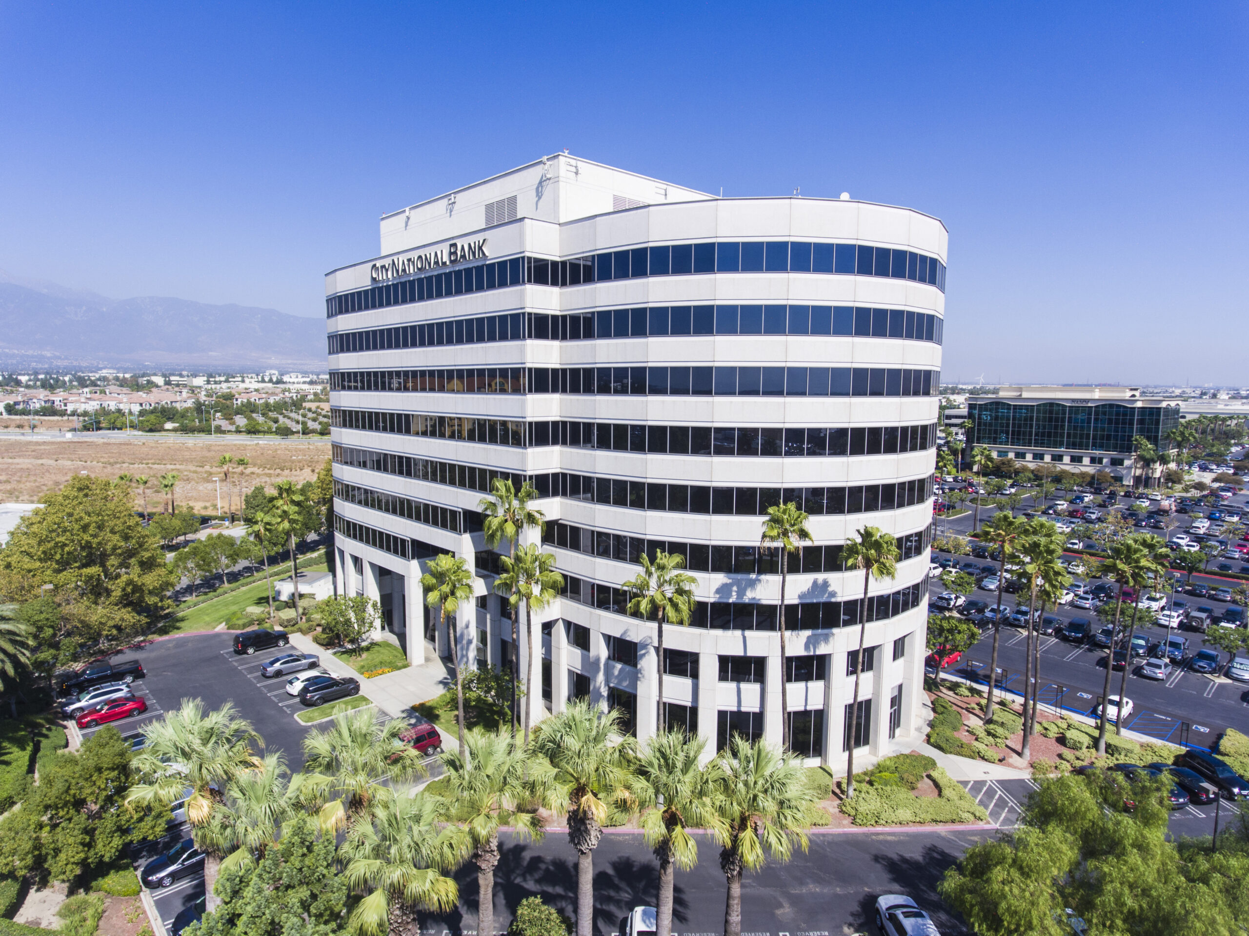 Aerial view of a multistory office building with landscaped grounds and surrounding parking areas.